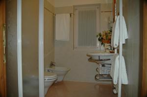 a bathroom with two sinks and a toilet and a window at Hotel Garni Civetta in Selva di Cadore