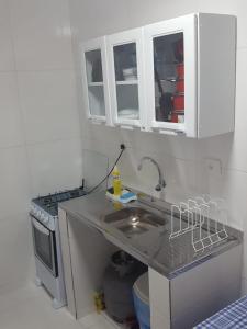 a kitchen with a sink and a stove and white cabinets at Porto de Galinhas - Flat 6 - Residencial Lagoa de Porto in Porto De Galinhas