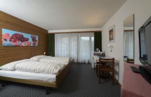 ヴェンゲンにあるアパートホテル レジデンス ベルナーホーフのベッド、デスク、テレビが備わるホテルルームです。