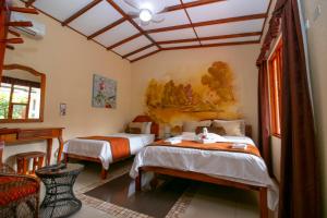 a bedroom with two beds and a table in it at Hotel La Rosa de America in Alajuela