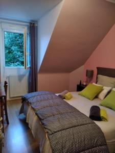 1 dormitorio con 2 camas con almohadas verdes y ventana en Chambres d'hôtes Les Chênes, en Acigné