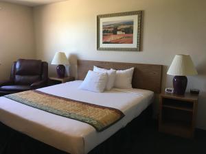 Habitación de hotel con cama y silla en Cassville Four Seasons Inn & Suites en Cassville