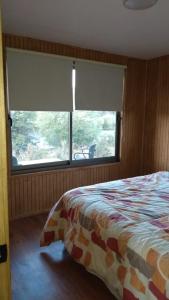a bedroom with a bed and a large window at Cabañas Tela in Lonquimay
