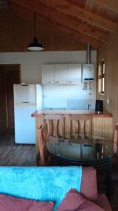 a kitchen with a glass table and a white refrigerator at Cabañas Tela in Lonquimay +16 photos