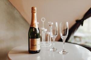 a bottle of champagne and two wine glasses on a table at Scandinave - In the Woods in Gesves