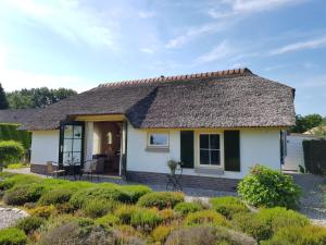 Ce cottage blanc est doté d'un toit de chaume. dans l'établissement Vakantiebungalow De Heivliet op de Veluwe, à Putten