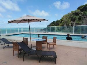 a table with an umbrella next to a swimming pool at Flet Beira-mar, Blue Sucet in João Pessoa