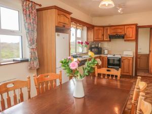 uma cozinha com uma mesa com um vaso de flores em Cleary Cottage em Miltown Malbay