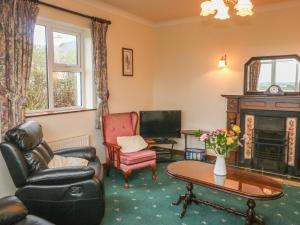 a living room with a couch chairs and a tv at Cleary Cottage in Milltown Malbay