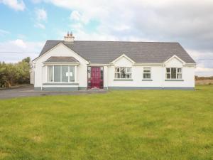 uma casa branca com uma porta vermelha e um quintal em Cleary Cottage em Miltown Malbay