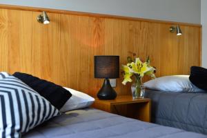 Un dormitorio con 2 camas y una lámpara y un jarrón de flores en Abisko Lodge, en Methven