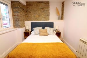 a bedroom with a large bed with a yellow blanket at Apartamentos Puerto Norte - Apto 1 in Puerto de Vega