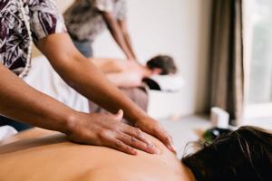 a woman getting a back massage from a therapist at The Pearl South Pacific Resort, Spa & Golf Course in Pacific Harbour