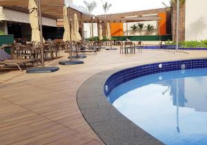 a swimming pool with tables and chairs and umbrellas at Apartamento Resort em Olímpia in Olímpia
