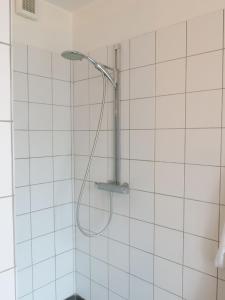 a shower with a shower head in a white tiled bathroom at ApartmentInCopenhagen Apartment 1354 in Copenhagen