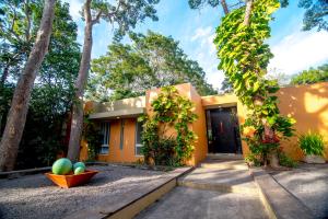 ein gelbes Haus mit einem Innenhof und Bäumen in der Unterkunft Htl & Villas Comala, alberca , parking, céntricas, Petfriendly in Comala