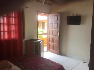 Habitación con cama y puerta con TV en Suites do Peró, en Cabo Frío