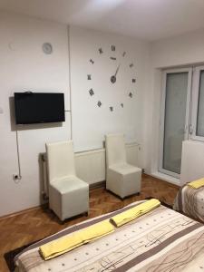 uma sala de estar com duas cadeiras e um relógio na parede em Majestic Rooms&Apartments em Prilep