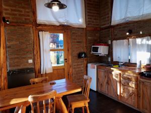 a kitchen with a wooden table and a table and chairs at Wilson Patagonia in Trevelín