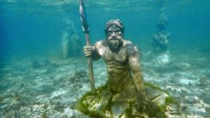 a statue of a man holding a spear in the ocean at Alegria Dive Resort in Alegria