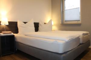 フィールンハイムにあるlooks-innのベッドルーム1室(白いシーツが備わるベッド2台、窓付)