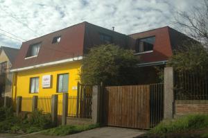 コンスティトゥシオンにあるHostal Casona del Cerroの褐色の屋根と柵の黄色い家