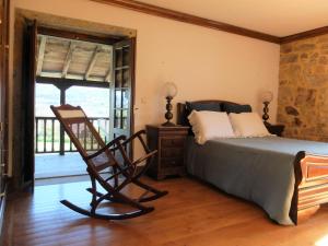 a bedroom with a bed and a chair and a balcony at Casas da Azenha do Rio in Barreiros +74 photos