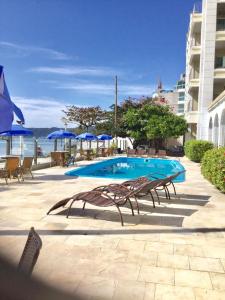uma piscina com cadeiras e guarda-sóis azuis em Apartamento Lexus Beira Mar - apt 101 em Florianópolis