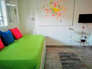 Un dormitorio con una cama verde y una pintura en la pared en Apartamento Las Orquideas en Mendoza