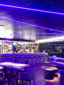 a bar with tables and chairs and purple lighting at J7 Plaza Hotel in Iloilo City