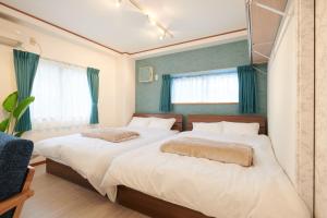 明石市にあるAwaji Portside Holiday Home CHOUTA - Self Check-In Onlyの緑のカーテンが備わるベッドルームのベッド2台