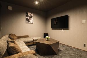 a living room with a couch and a tv at GRAND BASE Haruyoshi in Fukuoka