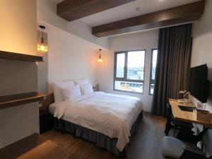 a hotel room with a bed and a desk at Watermark Hotel Kaohsiung Main Station in Kaohsiung