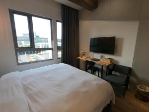 a hotel room with a bed and a television at Watermark Hotel Kaohsiung Main Station in Kaohsiung