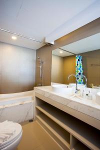 uma casa de banho com um lavatório, um WC e um espelho. em Coral Inn em Praia de Karon