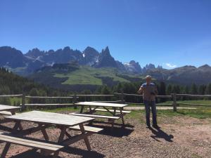 un hombre de pie junto a mesas de picnic en las montañas en B&B La Casa delle Bambole, en Panchia