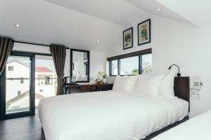 ein weißes Schlafzimmer mit einem großen Bett und Fenstern in der Unterkunft Le Petit Villa Hoi An in Hoi An