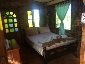 a bed in a room with two windows at Sunflowerbungalow in Khao Lak