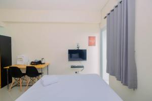 - une chambre avec un lit blanc, un bureau et une télévision dans l'établissement Cozy Studio Bogorienze Resort Apartment By Travelio, à Bogor