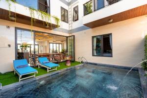 een zwembad in een huis met twee blauwe stoelen bij Seaweed Luxury Villa & Spa in Hội An