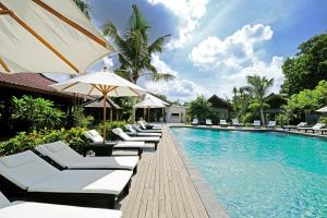 a pool with lounge chairs and an umbrella at Kashantee Village in Seminyak