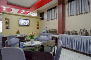 uma sala de jantar com mesas e cadeiras e uma televisão em RedDoorz Syariah @ Hotel Wisma Indonesia Kendari em Kendari