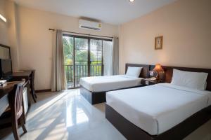 a hotel room with two beds and a desk and a window at Kong Garden View Resort Chiang Rai in Chiang Rai