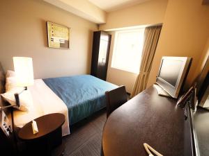 una camera d'albergo con letto, scrivania e tavolo di Hotel Route-Inn Gotenba Eki-Minami a Gotemba