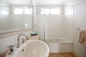 a bathroom with a tub, sink and mirror at Wavecrest Village & Tourist Park in Hopetoun