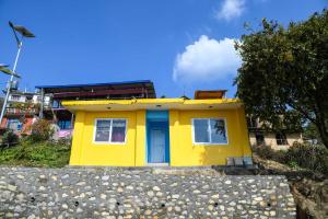 una casa amarilla con una puerta azul en una colina en Homestay in Nagarkot en Thimi