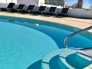 a swimming pool with blue water and lounge chairs at Quinta Pacifica Beachfront Villas in Rosarito
