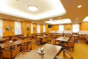 名古屋市にあるホテルルートイン名古屋栄の木製のテーブルと椅子が備わる空きレストランです。