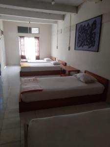 a room with three beds and a window at Beach Guest House in Maninjau