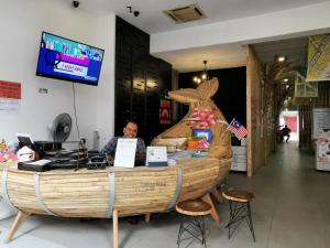 un hombre sentado en un mostrador con un barco de madera en Leo Leisure Hotel @ Central Market, en Kuala Lumpur